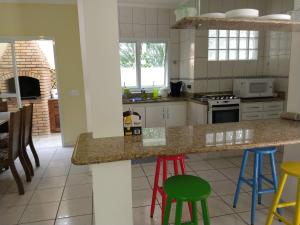 a kitchen with colorful stools at a counter at Villa Enseada - Charme e conforto a 650m da Praia da Enseada in Guarujá