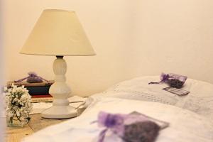 a white lamp sitting next to a bed with flowers on it at STECADÒ - Camera Lavanda in Dolceacqua