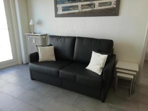 ein schwarzes Sofa mit zwei Kissen im Wohnzimmer in der Unterkunft Nevada in Koksijde