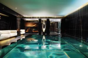 a swimming pool in a hotel room with a couch and a tub at Corinthia London in London