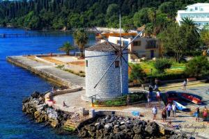 un molino de viento a orillas de un cuerpo de agua en Nafsika Luxury Suite en Corfú