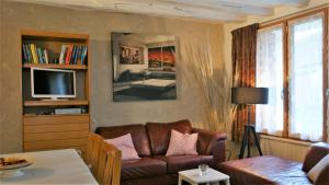 Una sala de estar con un sofá y un televisor. en LES LIMORNIERES, en Le Grand-Pressigny