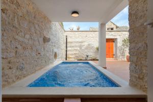 uma piscina numa casa com uma parede de pedra em Holiday home Rocca em Supetar