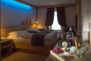 a bedroom with a bed and a table with wine glasses at Hotel Daniela in Livigno