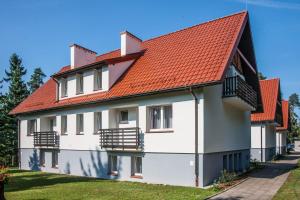 a white house with an orange roof at Resort Niegocin in Wilkasy