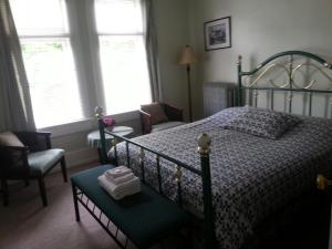 Schlafzimmer mit einem Bett, einem Stuhl und Fenstern in der Unterkunft Balfour House in Vancouver