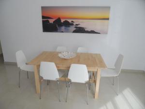 a dining room table with white chairs and a painting at PLAYA SAN JUAN, Casa Vacacional CENTRICA in Playa de San Juan