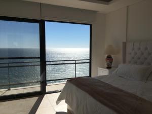 a bedroom with a large window with a view of the ocean at Pearl Tower Condo in Mazatlán +26 photos