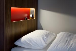 a bed with a white pillow and a wooden headboard at Loft - HI Hostel in Reykjavík