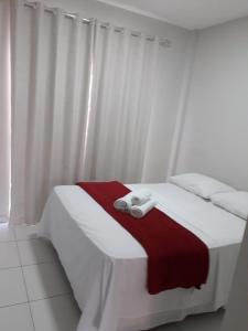a white bed with a red blanket and white towels on it at Hotel Ruy Barbosa in Eunápolis