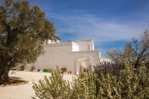 a large white building with trees in front of it at Masseria Cervarolo in Ostuni