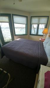 a bedroom with a large bed with two windows at Snug Harbor Inn in Sturgeon Bay