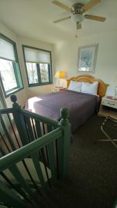 a bedroom with a bed with a fan and windows at Snug Harbor Inn in Sturgeon Bay