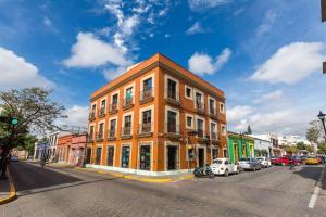 un grand bâtiment orange dans une rue de la ville avec des voitures dans l'établissement Oaxaca at your doorstep (3), à Oaxaca