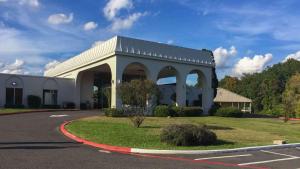 un gran edificio blanco con un arco en un aparcamiento en Studio 6-Longview, TX en Longview