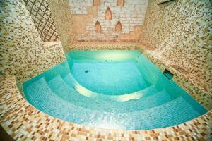 a large swimming pool in a building with blue water at Amur Hotel in Khabarovsk