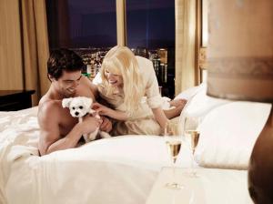 a man and woman sitting on a bed with a dog at Trump International Hotel Las Vegas in Las Vegas