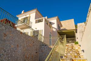 a house with stairs in front of a stone wall at Villa Giannanti in Porto Heli