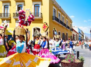 a group of girls in colorful skirts carrying baskets in a parade at Hotel Parador de Alcalá in Oaxaca City