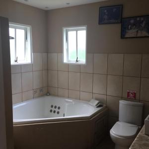 a bathroom with a tub and a toilet and two windows at Paraty Bungalows Bar E Hotel in Paraty