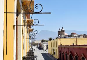 a city street with a yellow building at Hotel Parador de Alcalá in Oaxaca City