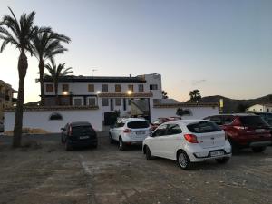 un grupo de autos estacionados en un estacionamiento frente a una casa en Hostal Mesón Arboleas en Arboleas