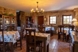 a restaurant with tables and chairs and a chandelier at Casa Rural as Bentinas in Milladoiro