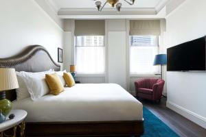 um quarto com uma cama branca e uma cadeira vermelha em The Beekman, A Thompson Hotel, by Hyatt em Nova York