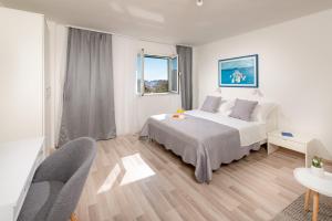 a white bedroom with a bed and a table and chairs at Apartment Adventure in Split