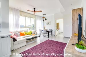 شقق كارميل البوتيكية في حيفا: غرفة معيشة مع أريكة بيضاء وسجادة أرجوانية