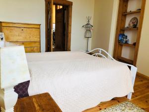 a bedroom with a white bed and a wooden floor at klusums in Liepāja +4 photos