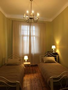a bedroom with two beds and a chandelier and a window at klusums in Liepāja