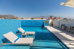 a swimming pool with two chairs and a table at Hotel Parador de Alcalá in Oaxaca City