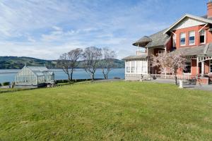 una casa grande con césped grande frente a un lago en St Leonards Lodge, en Dunedin