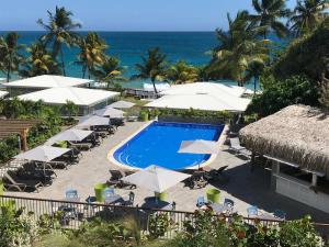 a resort with a pool and umbrellas and the ocean at Diamant les bains - Résidence Hôtelière in Le Diamant