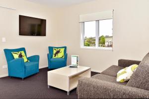 a living room with two chairs and a couch and a tv at Taupo Debretts Spa Resort in Taupo