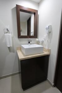 a white sink sitting under a mirror in a bathroom at Las Flores Beach Resort in Mazatlán