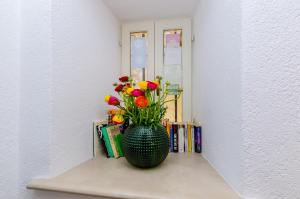 a vase with flowers sitting on a shelf with books at Villa Flores Studio Apartment in Dubrovnik