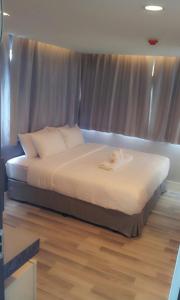 1 dormitorio con 1 cama grande con sábanas blancas en Nantra Ploenchit hotel en Bangkok