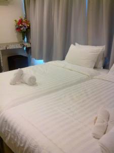 2 Betten mit weißer Bettwäsche und Handtüchern darauf in der Unterkunft Nantra Ploenchit hotel in Bangkok