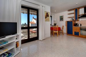 a living room with a television and a kitchen with a table at Apartment KIKA in Poreč
