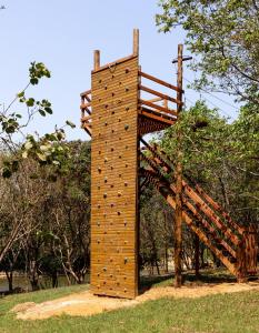 a wooden tower with a staircase in a park at Hotel Fazenda Ararita in Pôrto Feliz
