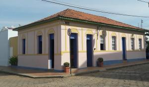 un bâtiment jaune et blanc avec des portes bleues dans une rue dans l'établissement Pousada Manga Rosa, à São João Batista do Glória