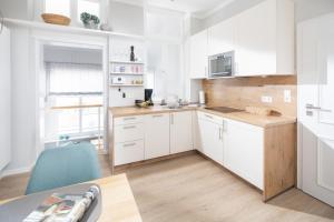 una cocina con armarios blancos y una silla azul en Fewo Ada, en Norderney