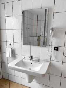 uma casa de banho branca com um lavatório e um espelho em Hotel Akazienhof em Duisburg