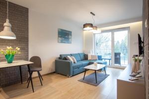 een woonkamer met een blauwe bank en een tafel bij Apartamenty Morski Florek in Kołobrzeg