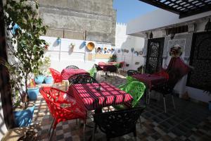 une terrasse avec des tables et des chaises rouges et vertes dans l'établissement Dar Essaki 1886, à Tanger