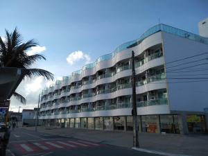 a large building with a palm tree in front of it at Manaíra Palace Residence in João Pessoa