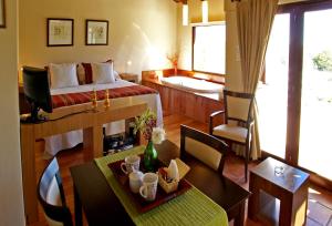 a room with a bed and a table and chairs at Las Ardillas Cabañas y Suites in La Falda