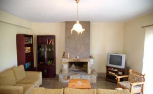 a living room with a fireplace and a tv at House Evia in Strópones
